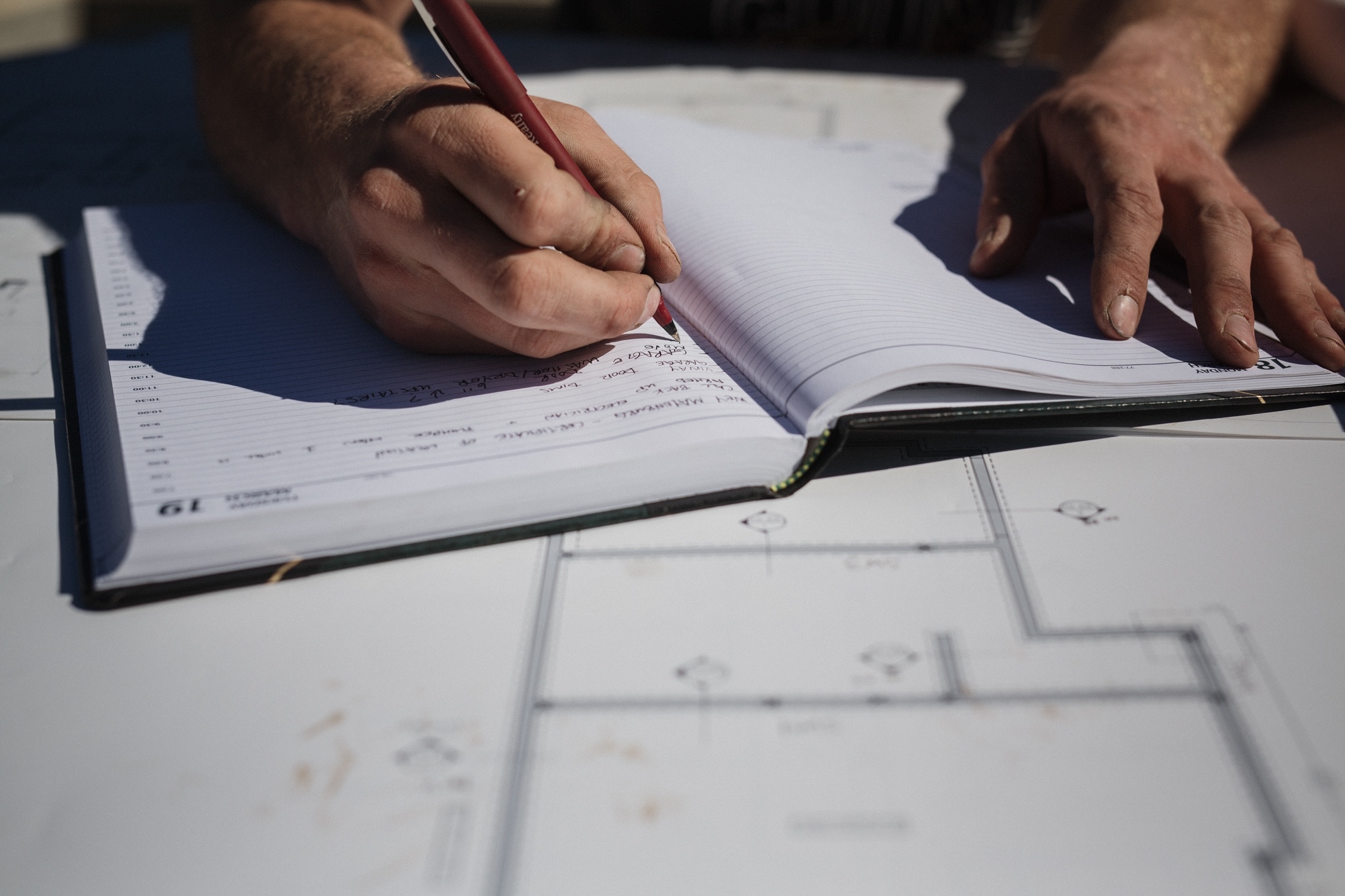 Adam writing notes on top of construction drawings